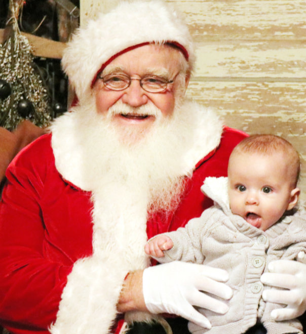 Santa pauses for a photo with Avaline Strehlow, after speaking with her parents, Aaron Strehlow and Kelsey Koopman at The Laurel Plantation during Laurel’s Night of Lights celebration Thursday night.
