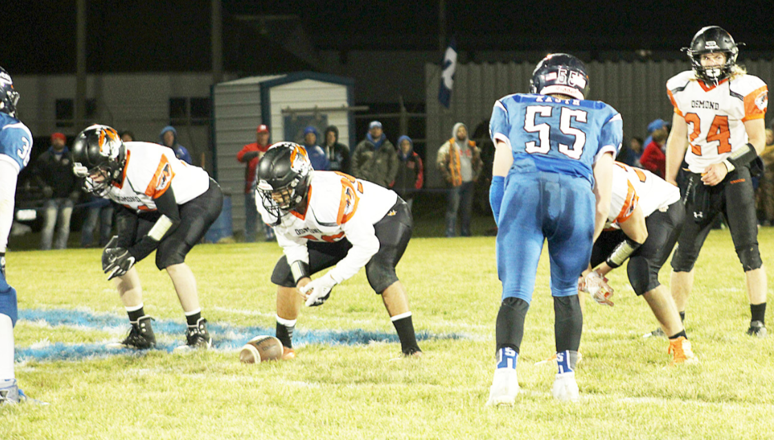 The Osmond Tigers (facing forward, with Anthony Heiman at far right) get set on the line during the playoff game against the Bloomfield Bees on Halloween night.